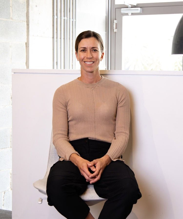 Erin, physiotherapist, sits comfortably on a chair with a welcoming smile